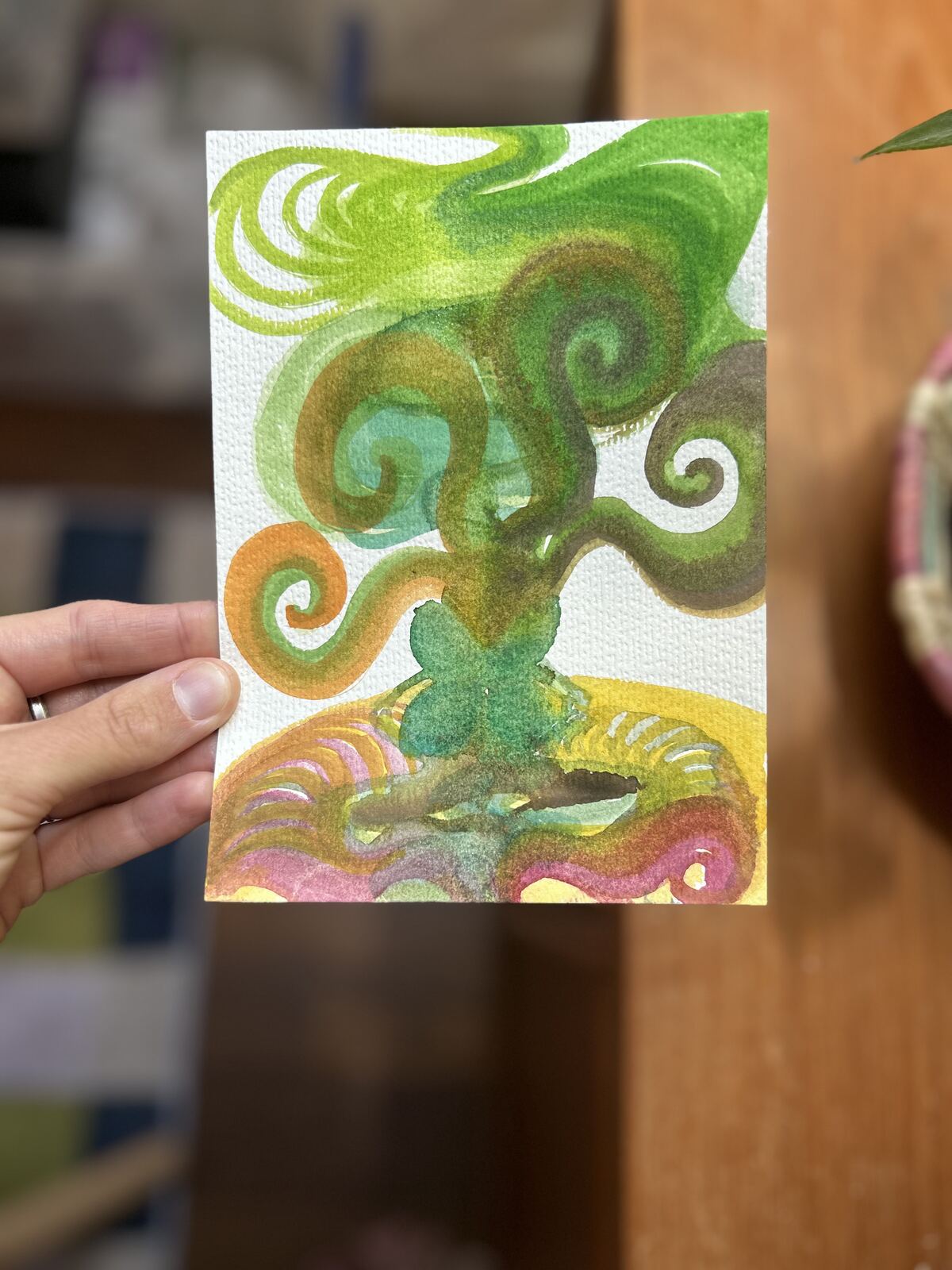 Small green watercolor faerie rooted down like a tree with spiraling branches, held in hand to represent energy of the faerie radiating out