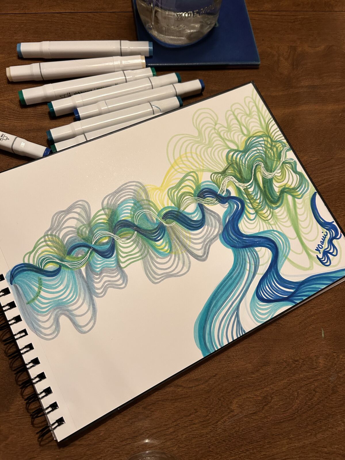Blue and green marker line drawing of a flowing, braided wave form in a sketchbook, signed x0alli